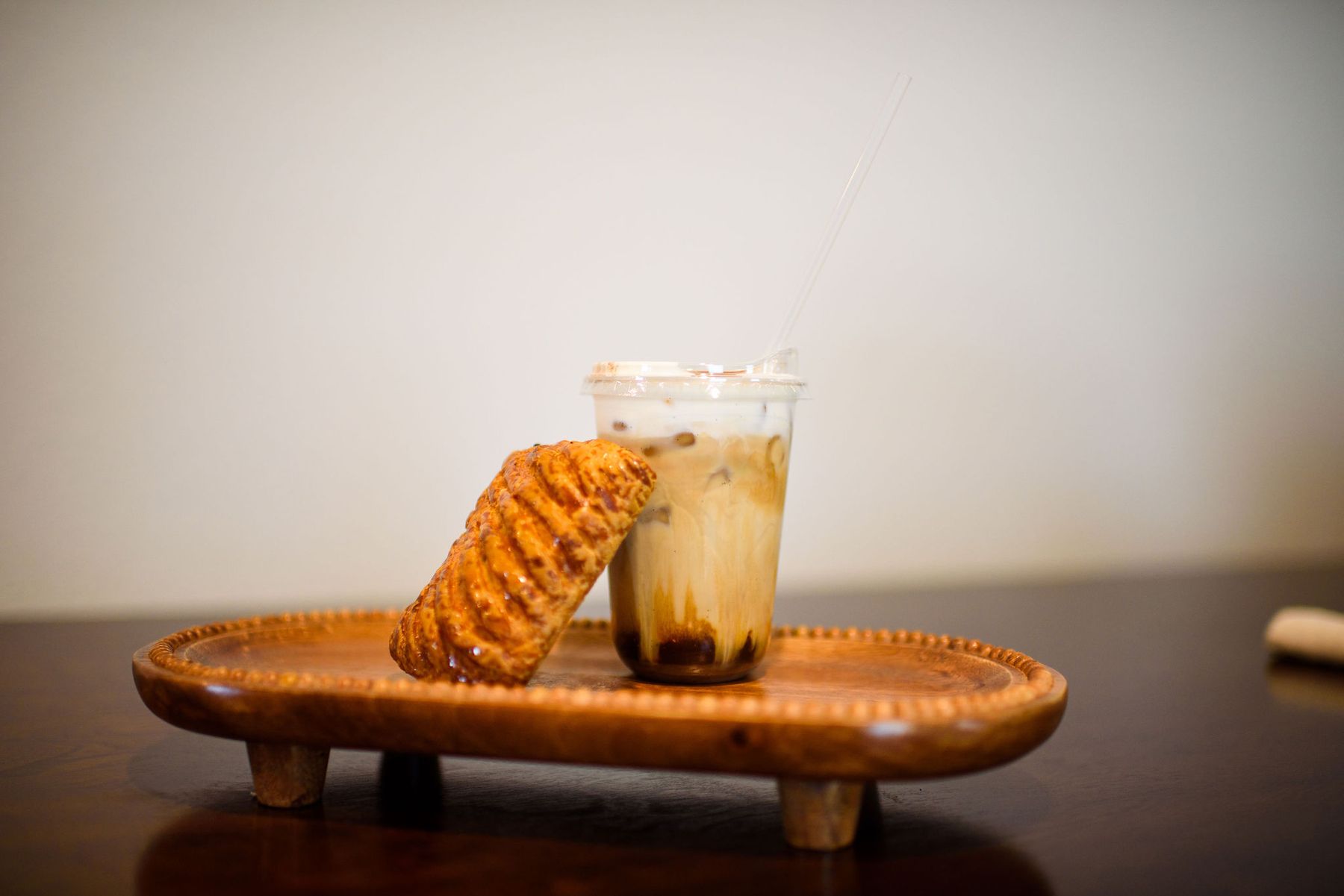 Iced latte with a pastry on a wooden tray
